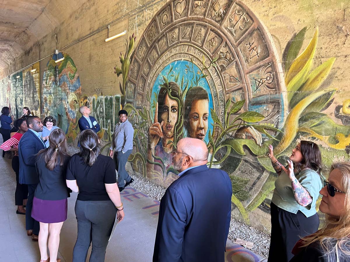 People on a tour of public space with colorful wall painting in background
